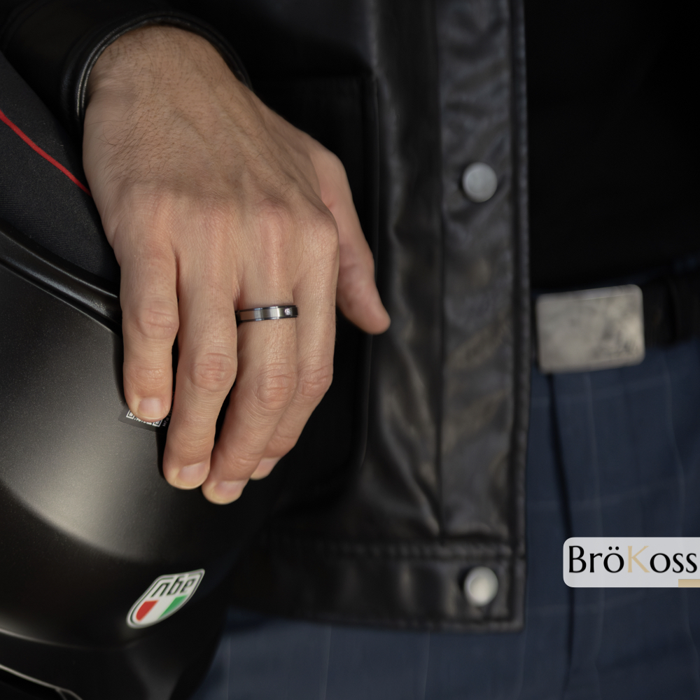 Anillo con diamantes hombre en zirconio negro gris sobre mano masculina apoyada en casco de moto