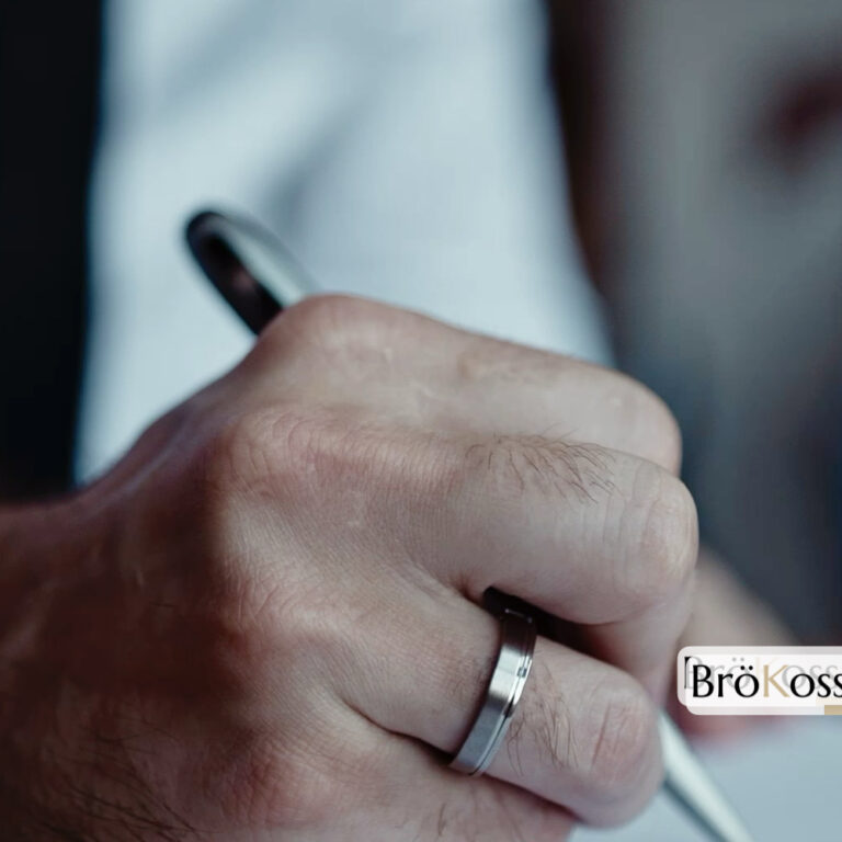 Anillo de hombre en zirconio gris con borde pulido y cuerpo mate en mano masculina escribiendo, detalle de diseño