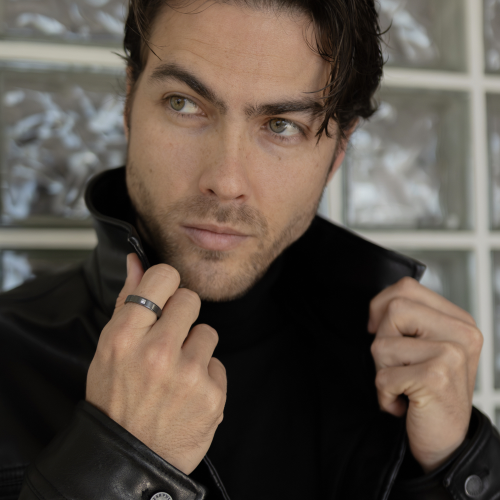 Detalle de anillo brillante hombre en zirconio negro con brillante cuadrado y bordes pulidos en mano de modelo elegante