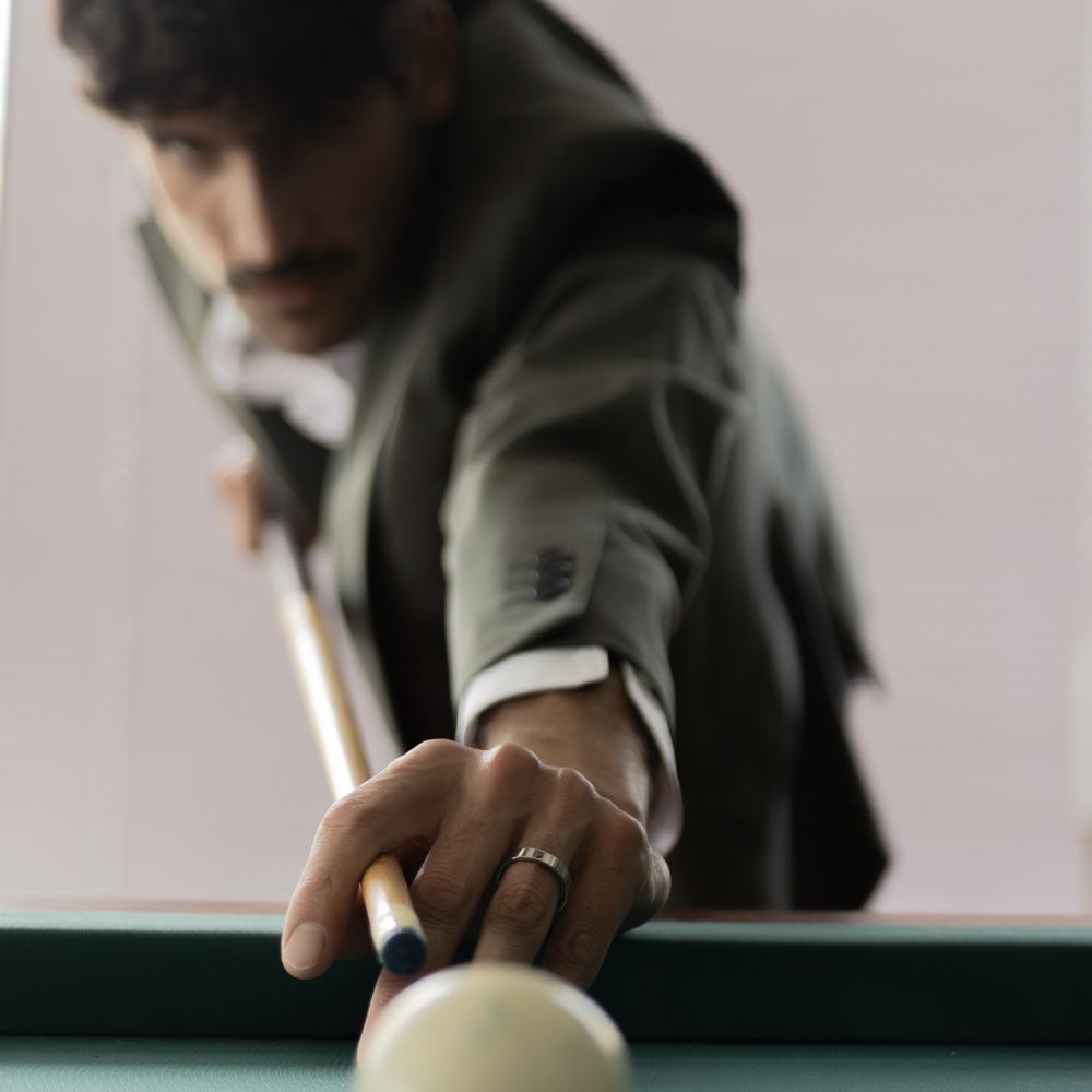 Anillo con piedra hombre en zirconio gris con diamante negro en mano de modelo masculino elegante con palo de billar