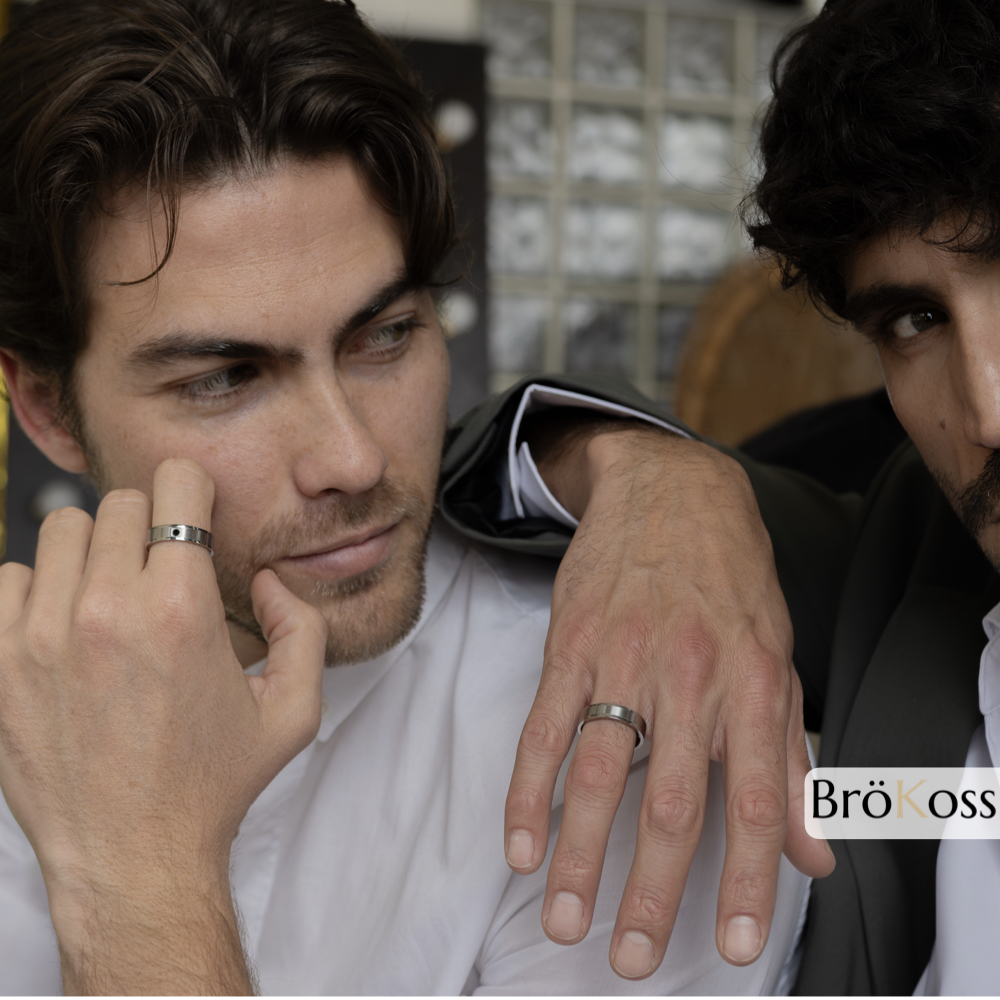 Dos modelos masculinos, uno lleva anillo de diamante negro, estilo moderno y sofisticado
