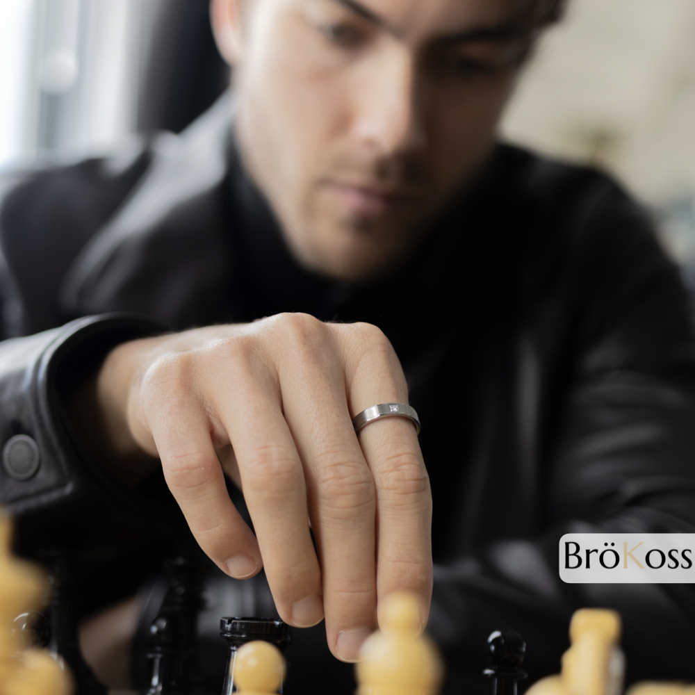 Anillo de diamante para hombre en mano mientras juega al ajedrez, joya elegante