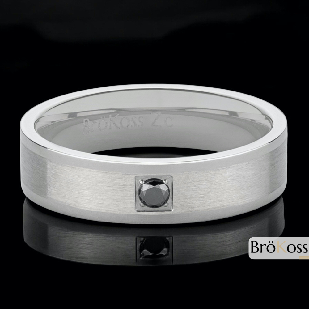 Anillo diamante negro hombre, zirconio gris con bordes pulidos y centro mate, colocado sobre fondo elegante