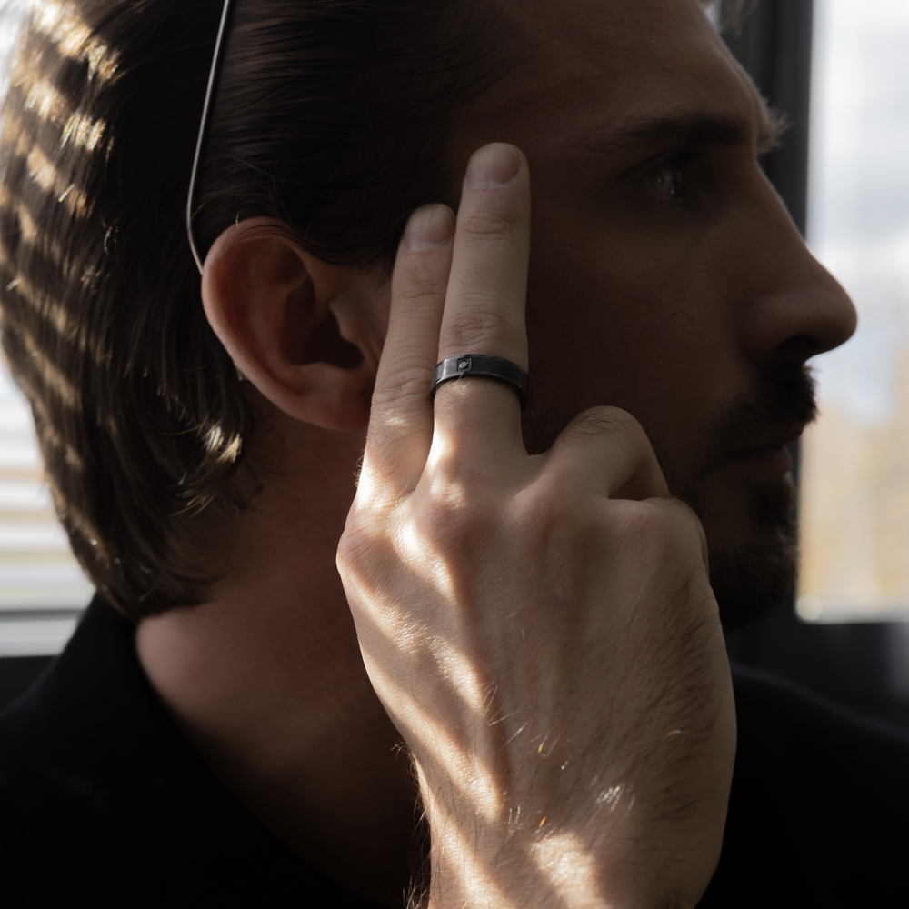 Anillo piedra hombre en zirconio negro con diamante negro natural, en mano de modelo masculino apoyada en cabeza
