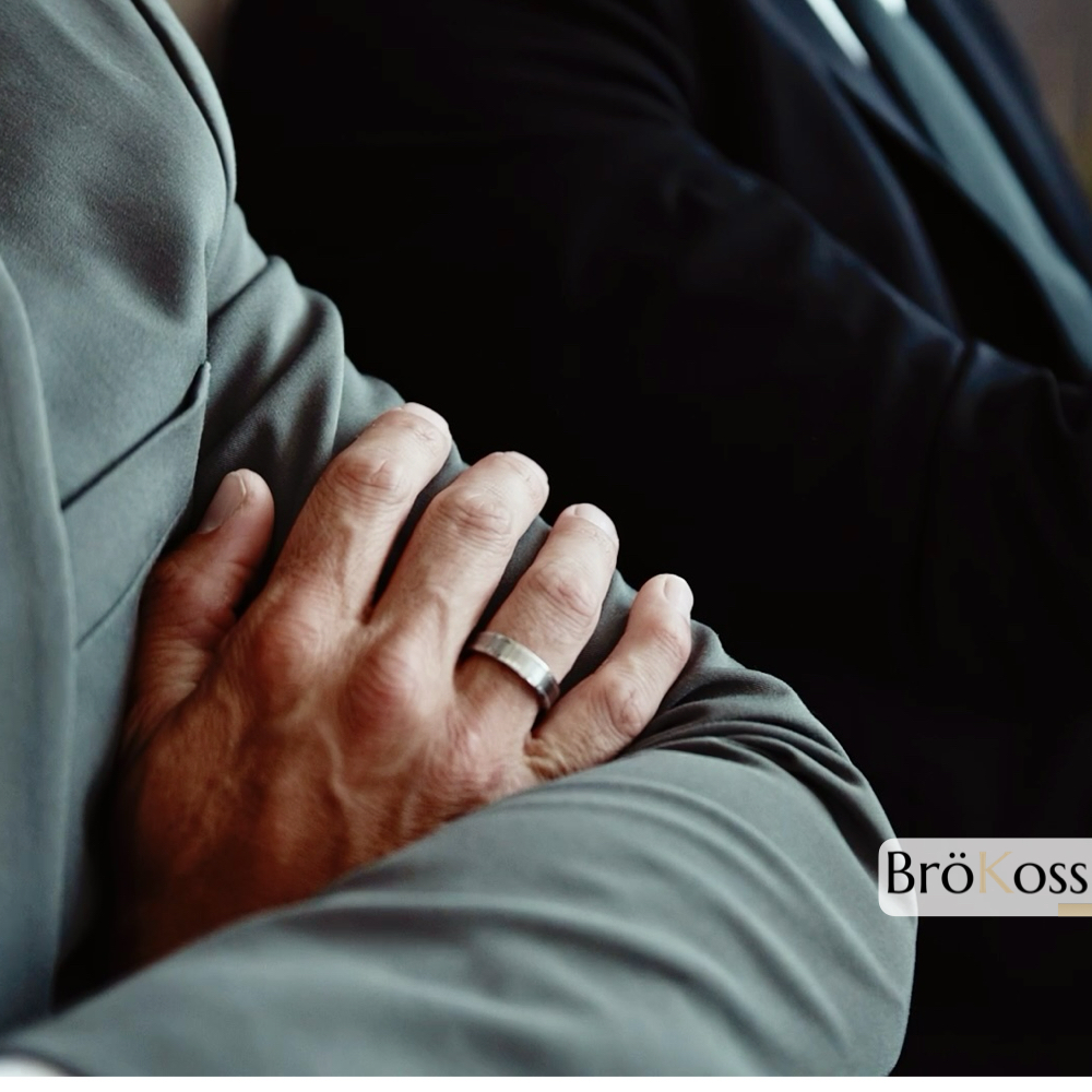 Dos hombres mostrando compromiso, uno con anillo de zirconio gris plateado estilo oro blanco